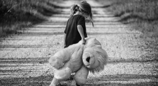 Lonely girl dragging a large teddy.